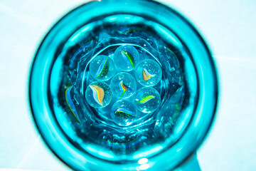 abstract photo with colorful glass balls in blue glass with water, fantastic background