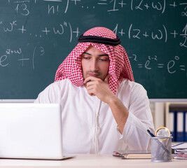 Arab teacher in front of chalkboard