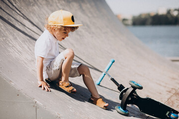 Cute little boy with curly hair riding scooter