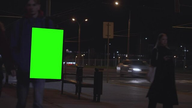 Big citylight with green chromakey for advertising installed at transport stop. City life depicted at accelerated pace at night time lapse