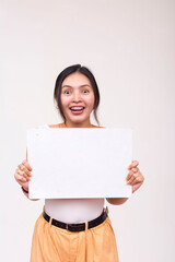 Naklejka premium A surprised young Asian woman standing straight while holding a white blank placard. Isolated on a white background.