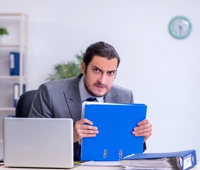 Young male employee unhappy with excessive work in the office