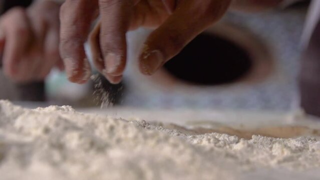 Dough and Flour Being Picked Up and Rolled By Master Baker in Traditional Bakery in Slow Motion