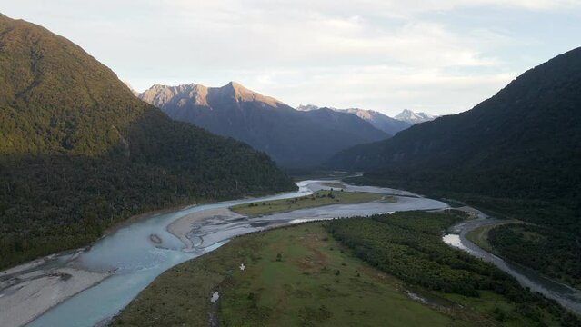 Picturesque mountains with the peaks bathed in orange sunset light,  aerial pedestal
