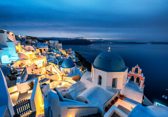 Image of white church in Oia with blue dome before sunrise during blue hour, Santorini, Greece