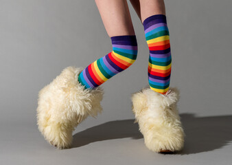 Unrecognizable girl in striped socks and boots on gray floor