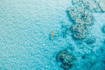 Woman swim in blue ocean on her vacations. Aerial view, top view
