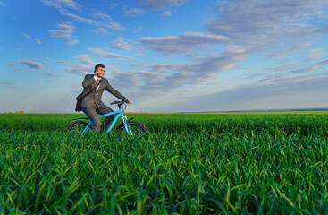 a businessman rides a bicycle on a green grassy field, dressed in a business suit, he makes a phone call, beautiful nature in spring, freelance business concept