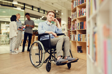 Portrait of content young person with disability student boy with headphones on neck sitting in...