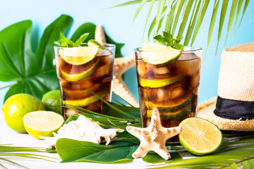 Summer drink. Cuba Libre or iced tea with palm leaves and sea shells. Tropical vacation.