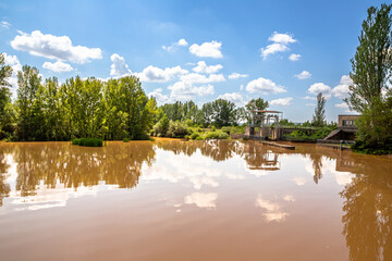 Obraz premium General view of the San Andrés dam of the Canal de Castilla with cloudy water on a sunny day, Herrera de Pisuerga, Palencia, Spain