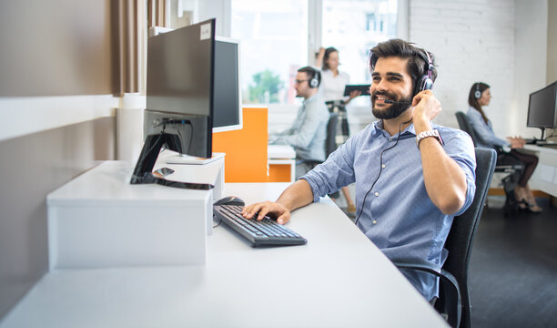 Handsome male employee telephone worker with headset assisting to client while having conversation during online phone call at customer support center.