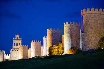 Fototapeta na wymiar Night view of the north wall and belfry of the Puerta del Carmen in the walled city of Avila, Spain