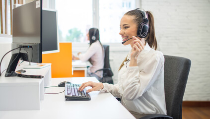 Smiling customer support female phone worker consulting and assisting client via phone call.