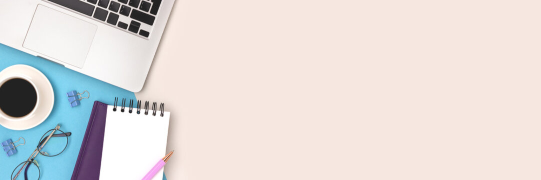 Banner with with laptop, cup of coffee, eyeglasses and stationery on a blue and gray background. Business workspace.