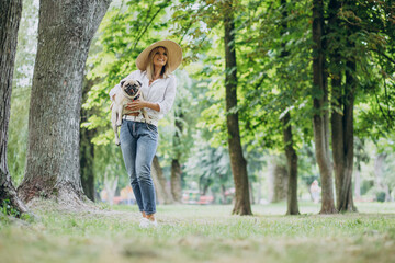 Woman having a walk in park with her pug-dog pet