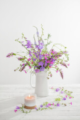 summer wild  flowers  in white jug on white background