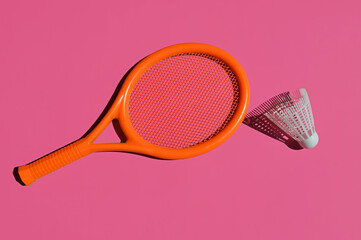 a badminton game, a small orange racket and a shuttlecock. sports summer entertainment. background for the design