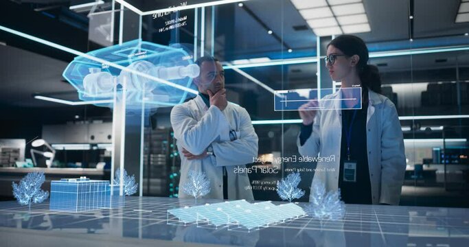 Male And Female Industrial Engineers Using Futuristic Animated Hologram of Wind Turbine Prototype In Computer Powered Laboratory. Multiethnic Colleagues Controlling VFX Projection With Gestures.