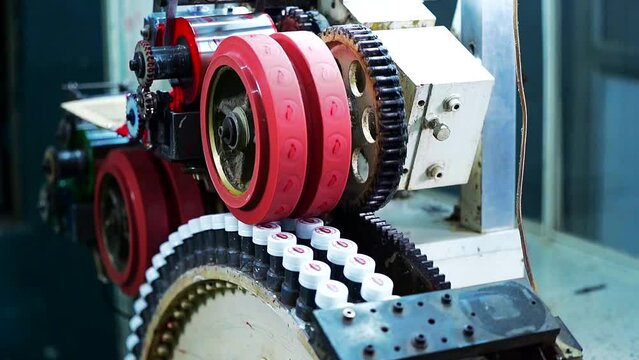 A close-up of a machine punching or stamping the logo of company on a bottle cap. Plastic bottle factory.