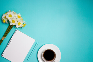 Blue concept of working items with coffee cup, notebook and flowers with copy space.