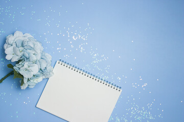 Blank notebook with flowers on a glitter and blue background. 