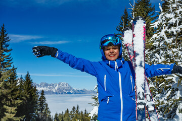 Child on alpine snow slope stretching and raising his hands high