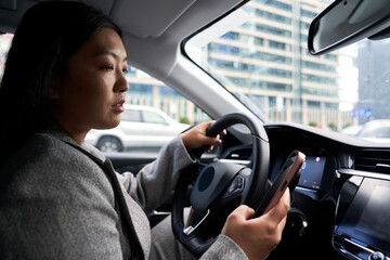Chinese woman using mobile phone while driving a car