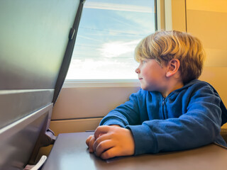 Little boy sit looking at the window in high speed train