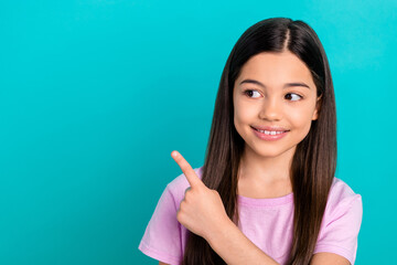 Photo of dreamy sweet little child dressed pink t-shirt showing finger looking empty space isolated teal color background