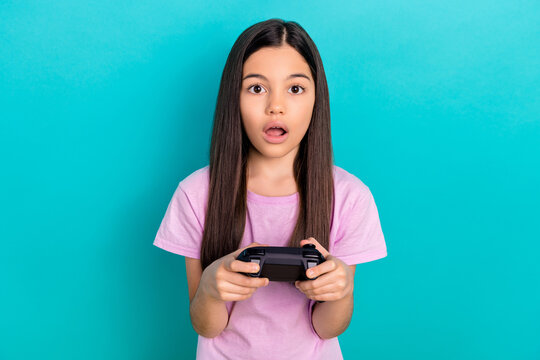 Crazy emotion of young funny girl hold joystick surprised playing free time fortnite lose tournament isolated on blue color background