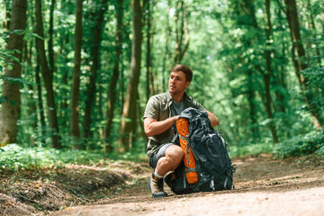 Opening the backpack. Tourist in summer forest. Conception of exploration and leisure