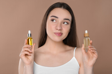 Fototapeta premium Woman with bottles of essential oil on brown background