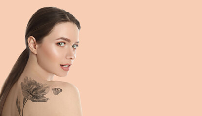 Young woman with beautiful tattoo of flower and butterfly on pale peach background, space for text. Banner design