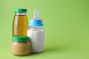 Healthy baby food, juice and milk on green background, space for text