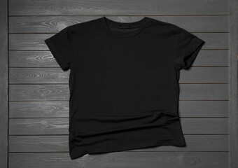 Stylish black T-shirt on gray wooden table, top view