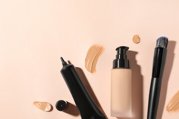 Liquid foundations, swatches and makeup brush on beige background, flat lay. Space for text