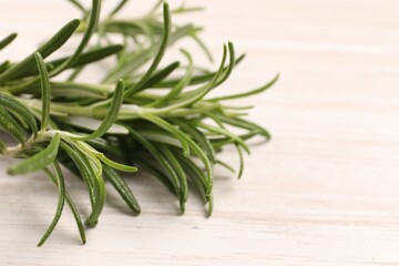 Fresh green rosemary on white wooden table, closeup. Space for text