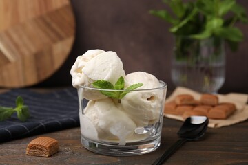 Scoops of ice cream with mint leaves and caramel candies on wooden table, closeup