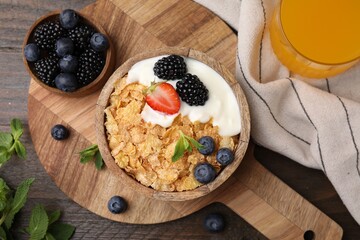 Delicious crispy cornflakes, yogurt and fresh berries served on wooden table, flat lay. Healthy breakfast