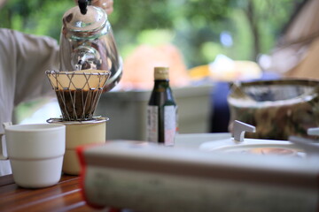 キャンプの朝食でドリップコーヒーを入れる女性