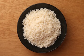 Plate with delicious rice on wooden table, top view
