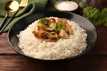 Delicious rice with mushrooms and parsley on wooden table, closeup