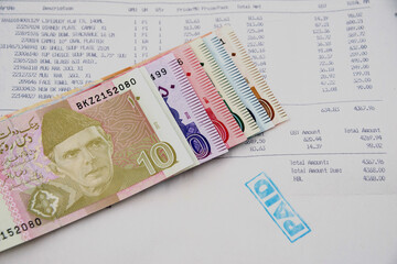 Currency notes in Pakistani Rupees with a paid invoice.