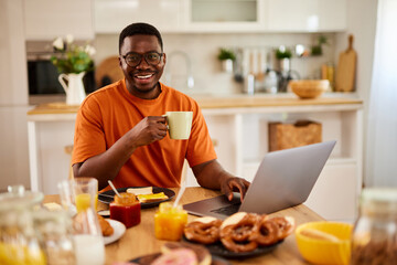 Fototapeta na wymiar African American man using laptop while enjoying breakfast at home