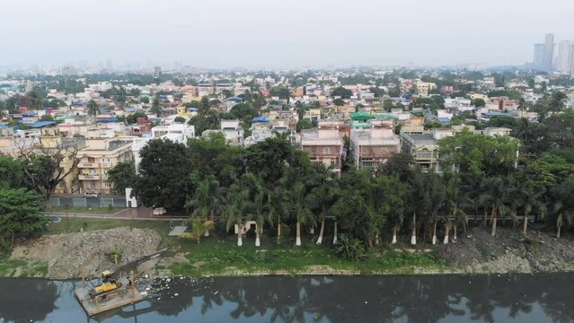Aerial view of beautiful island with palm trees pond and rows of buildings in a part of Kolkata, India.