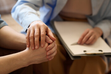 Close-up of therapist supporting her patient at session holding his hand and talking to him