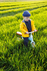 A little boy rides a blue balance bike, running bike. A happy child is learning to balance on an exercise bike in the garden. A child is playing on the street. First day on the bike.