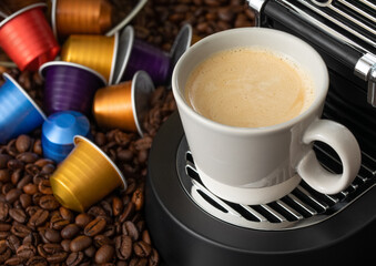 White cup with hot coffee from espresso machine pods on beans background.