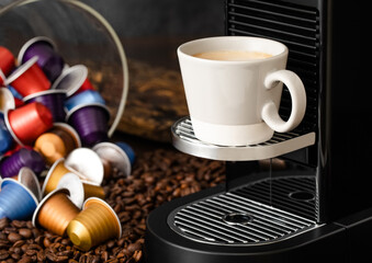 Coffee capsules pods on raw beans background with espresso cup and home coffee machine.